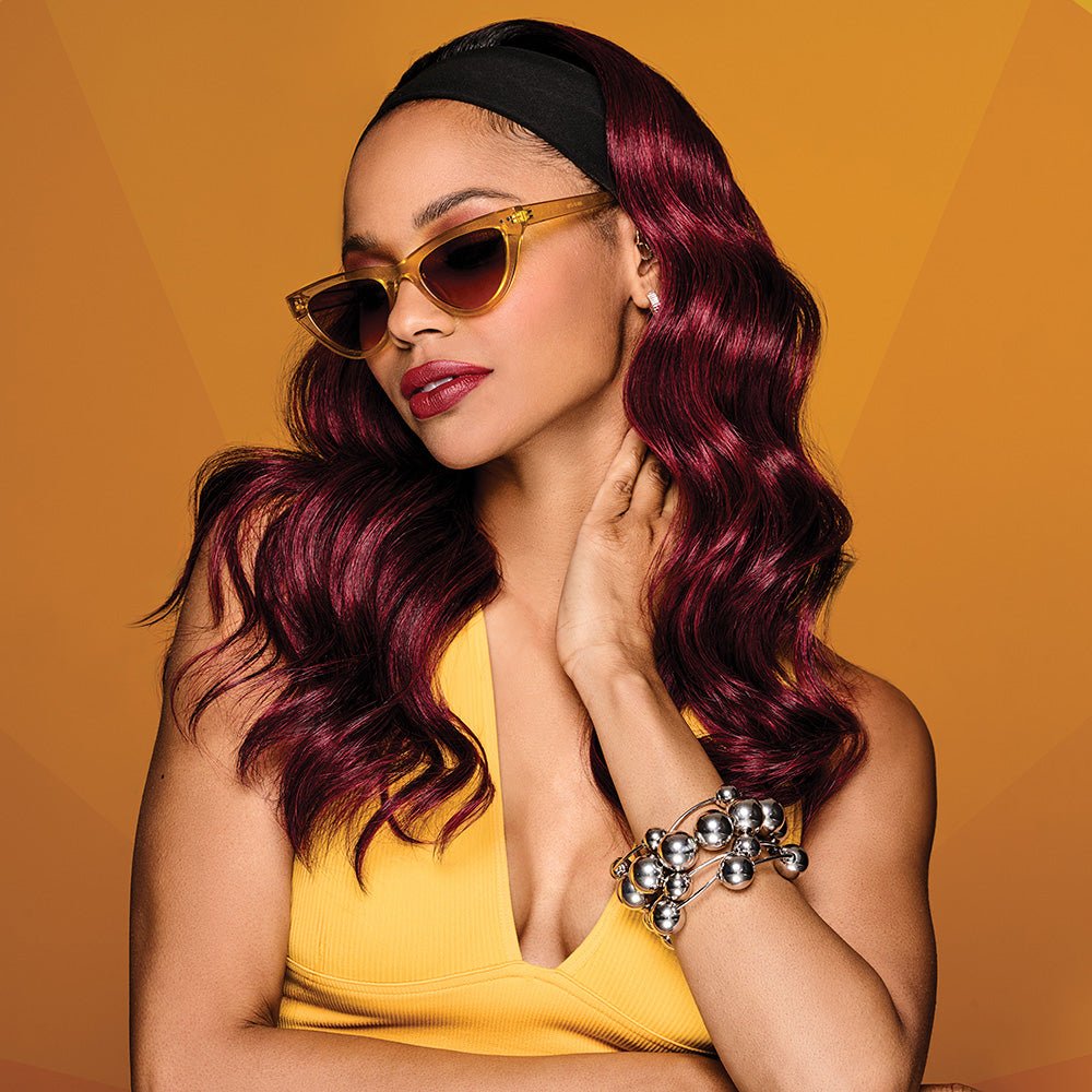 Woman wearing 20in Wavy Waves Headband Wig in Sangria while tilting her head to the left - View from the front