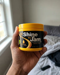Hand holding product in a natural bedroom setting near a window