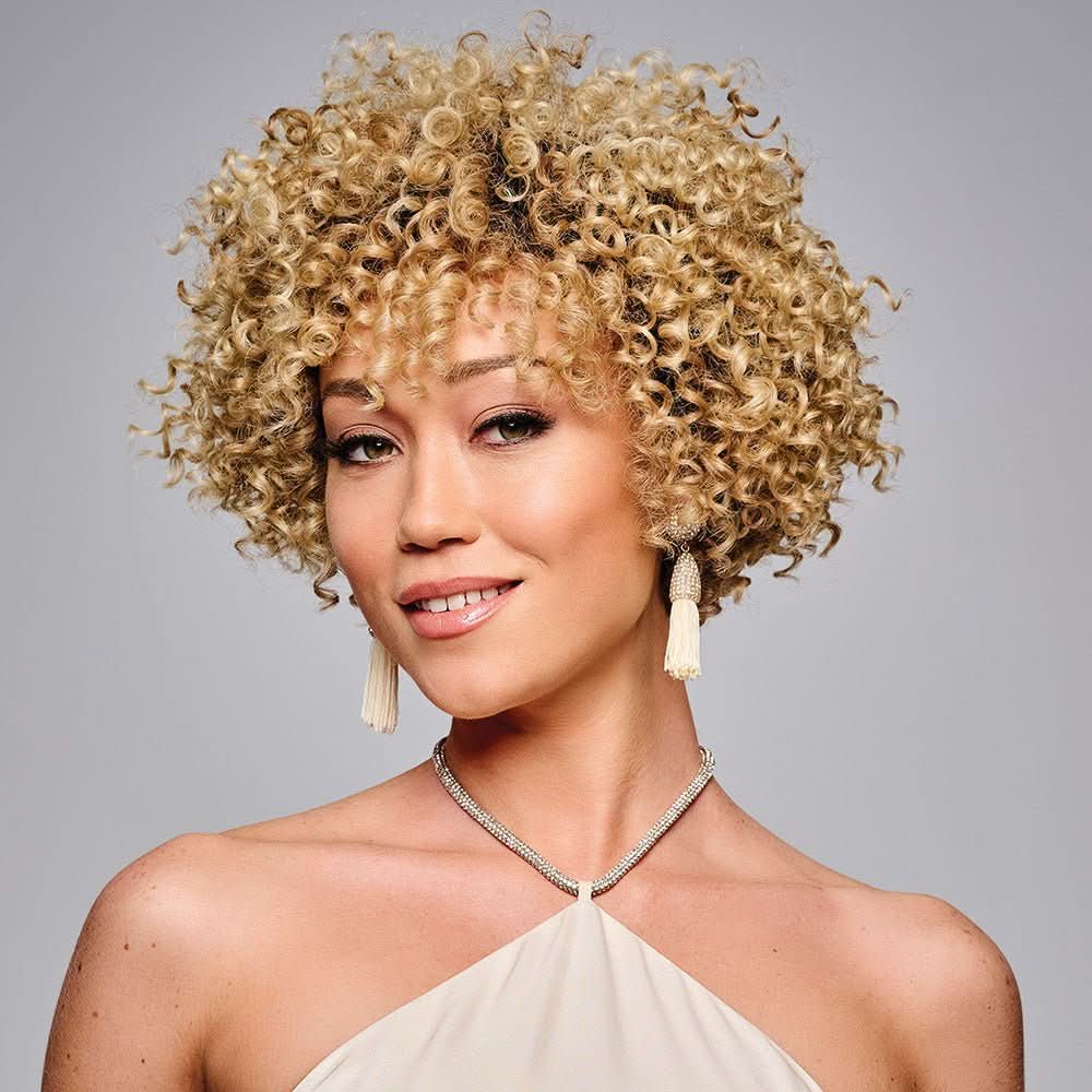 Woman wearing Zahra Wig in Honey while slightly turning her head - View from the front